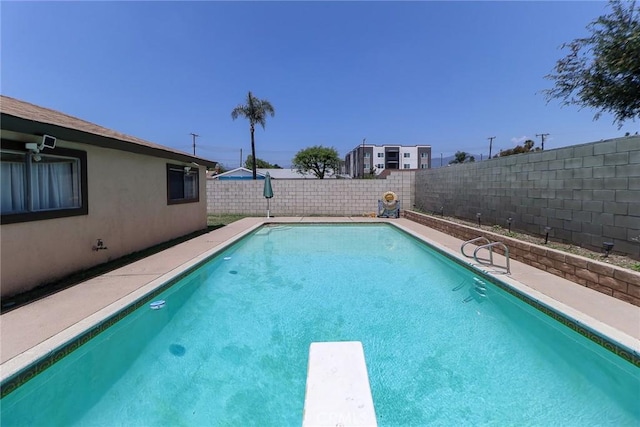 view of swimming pool featuring a fenced backyard and a diving board