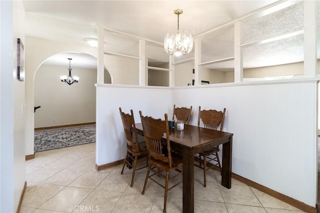 dining area with a chandelier, arched walkways, baseboards, and tile patterned floors