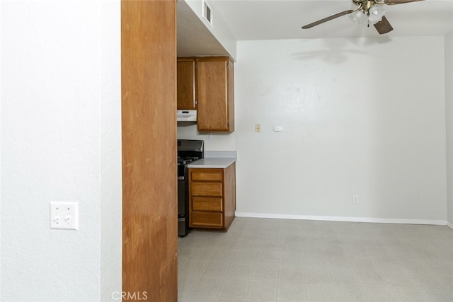 2807 W W Ave K12, Unit 256, Lancaster, CA 93536 - kitchen with black range with gas stovetop, under cabinet range hood, a ceiling fan, brown cabinets, and light countertops