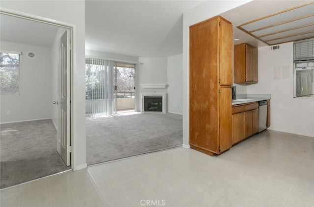 2807 W W Ave K12, Unit 256, Lancaster, CA 93536 - kitchen with brown cabinetry, stainless steel dishwasher, light colored carpet, a fireplace, and open floor plan