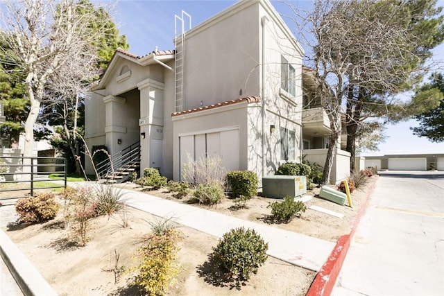 2807 W W Ave K12, Unit 256, Lancaster, CA 93536 - view of front of house with stucco siding, fence, stairway, a tile roof, and a detached garage