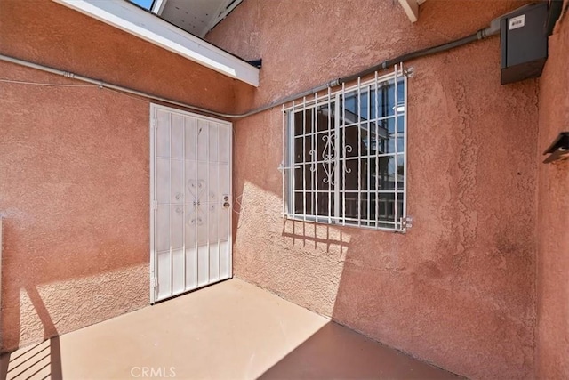 entrance to property with stucco siding and a patio
