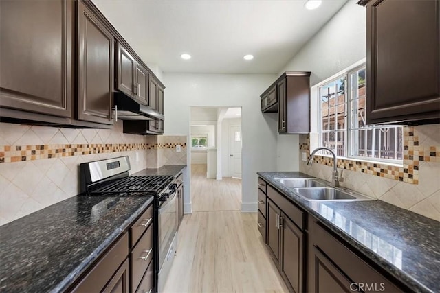kitchen featuring stainless steel range with gas cooktop, a sink, dark brown cabinets, healthy amount of natural light, and recessed lighting