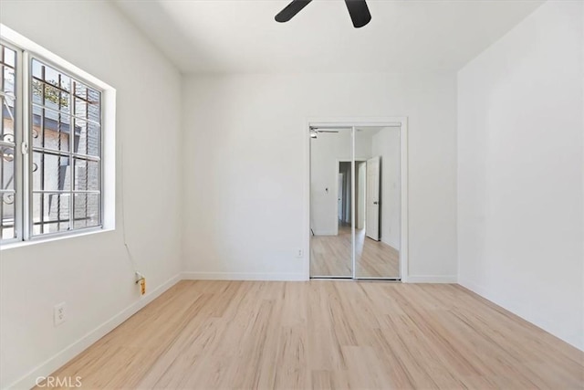 empty room with ceiling fan, wood finished floors, and baseboards