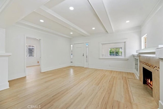 unfurnished living room with a tile fireplace, light wood-style floors, beam ceiling, ornamental molding, and recessed lighting
