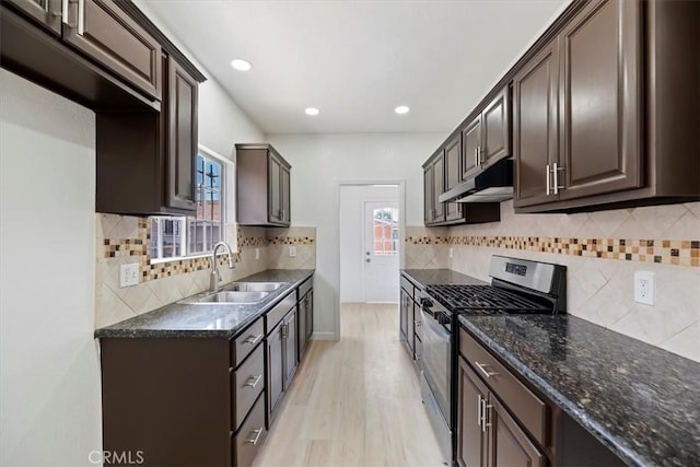 kitchen featuring stainless steel range with gas stovetop, a sink, under cabinet range hood, dark brown cabinetry, and recessed lighting