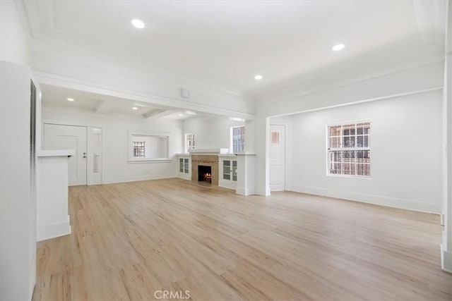 unfurnished living room featuring light wood-style floors, recessed lighting, a lit fireplace, baseboards, and beam ceiling