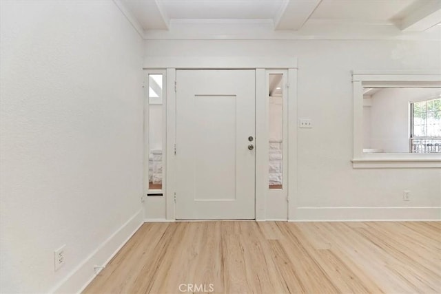 foyer featuring wood finished floors, ornamental molding, and baseboards