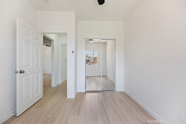 unfurnished bedroom featuring light wood finished floors, a closet, and baseboards