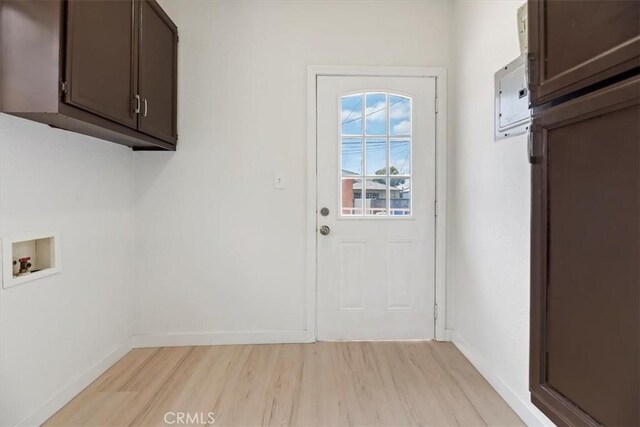 laundry room with cabinet space, light wood-type flooring, hookup for a washing machine, and baseboards
