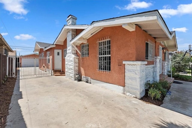 view of front of property with fence, a chimney, stucco siding, and driveway