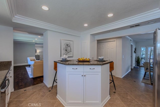 1448 W Domingo Rd, Fullerton, CA 92833 - kitchen with a breakfast bar, white cabinetry, light tile patterned floors, dark stone counters, and ornamental molding