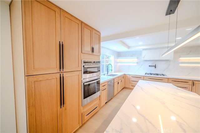 kitchen with light brown cabinets, stainless steel appliances, a sink, light stone countertops, and recessed lighting