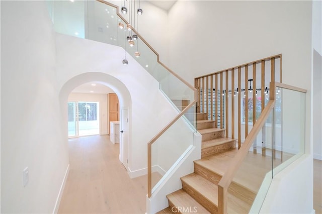24701 Sarah Ln, Lake Forest, CA 92630 - staircase featuring a towering ceiling, arched walkways, wood finished floors, and baseboards