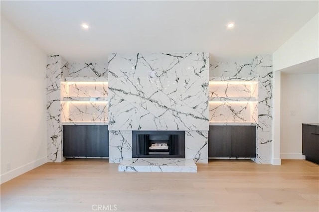unfurnished living room with recessed lighting, an accent wall, baseboards, and wood finished floors