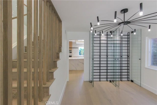 unfurnished dining area featuring wood finished floors, a chandelier, and baseboards