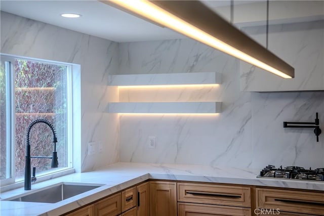 kitchen with a sink, light stone counters, backsplash, stainless steel gas cooktop, and recessed lighting