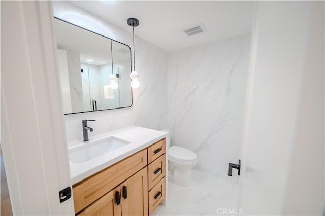 bathroom with vanity, toilet, marble look tiles, and a marble finish shower