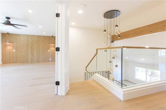 stairway with wood finished floors, recessed lighting, ceiling fan, and wood walls