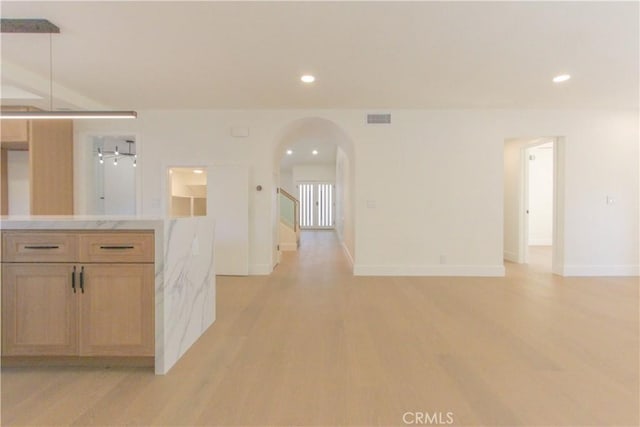 kitchen featuring arched walkways, light wood-style floors, light countertops, recessed lighting, and baseboards