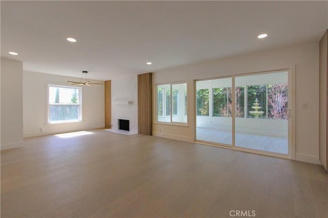 unfurnished living room with light wood-style floors, recessed lighting, a fireplace, and baseboards