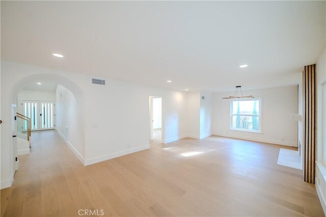 unfurnished room with arched walkways, light wood-style floors, recessed lighting, and baseboards