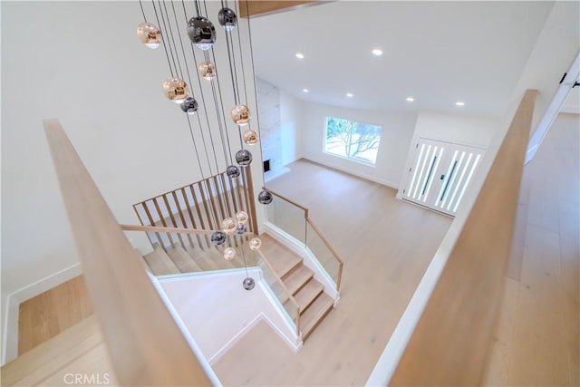 stairs with wood finished floors, recessed lighting, and baseboards