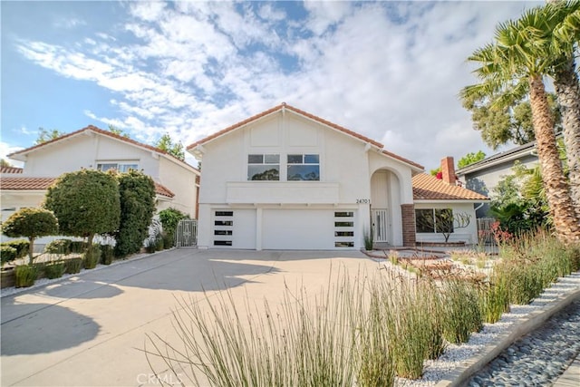 mediterranean / spanish-style house with a garage, concrete driveway, a tiled roof, and stucco siding
