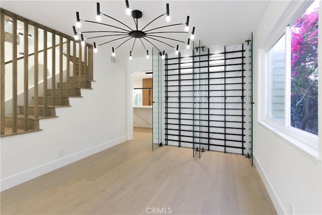 spare room with wood finished floors, baseboards, and a chandelier