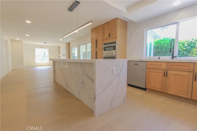 kitchen with appliances with stainless steel finishes, a sink, recessed lighting, light wood-style floors, and hanging light fixtures
