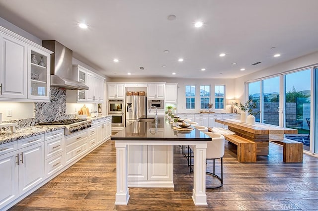 47 Cielo Azul, Mission Viejo, CA 92692 - kitchen with wall chimney range hood, stainless steel appliances, recessed lighting, white cabinetry, and a kitchen breakfast bar