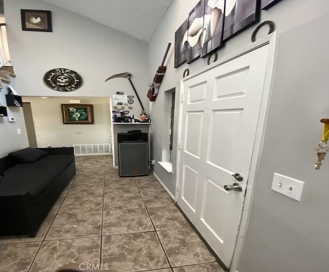 hallway with tile patterned floors and lofted ceiling