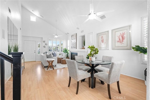 2 Chestnut Dr, Aliso Viejo, CA 92656 - dining area with high vaulted ceiling, ceiling fan, a glass covered fireplace, light wood-style flooring, and baseboards