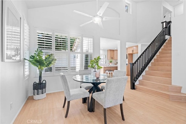 2 Chestnut Dr, Aliso Viejo, CA 92656 - dining space featuring light wood finished floors, a ceiling fan, stairs, baseboards, and a high ceiling