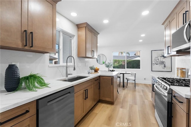 109 Loyola, Seal Beach, CA 90740 - kitchen with appliances with stainless steel finishes, a sink, light wood-style flooring, tasteful backsplash, and light stone countertops