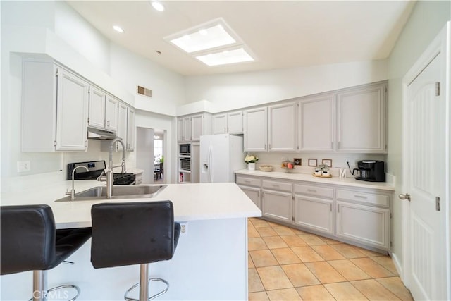 16395 Cuyama Way, Apple Valley, CA 92307 - kitchen with white fridge with ice dispenser, a peninsula, under cabinet range hood, a sink, and a breakfast bar