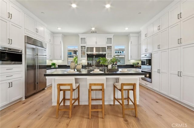 56 Chasma, Irvine, CA 92618 - kitchen featuring stainless steel appliances, a kitchen bar, white cabinets, dark countertops, and recessed lighting