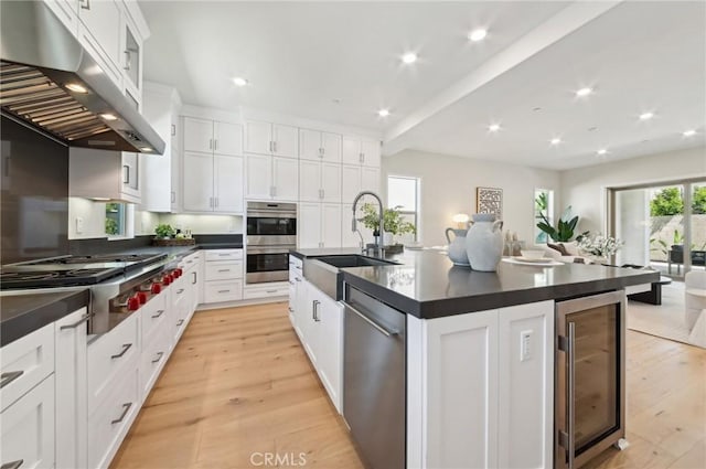56 Chasma, Irvine, CA 92618 - kitchen with under cabinet range hood, stainless steel appliances, a sink, wine cooler, and dark countertops