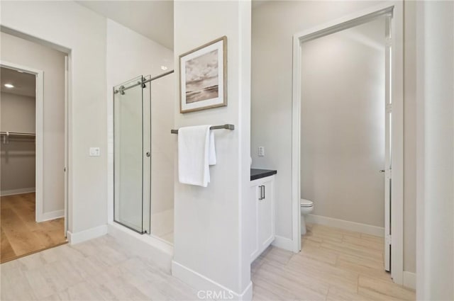 56 Chasma, Irvine, CA 92618 - bathroom featuring a shower stall, toilet, wood finished floors, baseboards, and a spacious closet