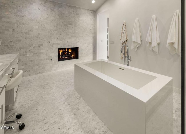 bathroom with a fireplace, a freestanding bath, and recessed lighting