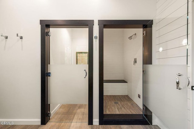 bathroom with wood finished floors and a stall shower