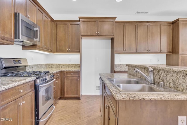 40197 Gallatin Ct, Temecula, CA 92591 - kitchen with stainless steel appliances, a sink, light wood finished floors, brown cabinetry, and recessed lighting