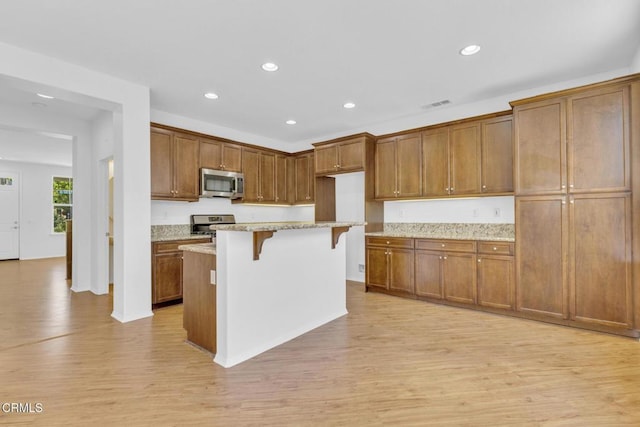 40197 Gallatin Ct, Temecula, CA 92591 - kitchen with appliances with stainless steel finishes, light wood finished floors, a breakfast bar area, brown cabinets, and recessed lighting