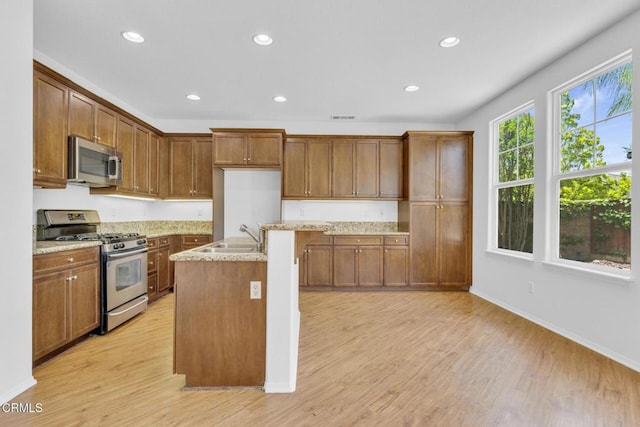 40197 Gallatin Ct, Temecula, CA 92591 - kitchen featuring appliances with stainless steel finishes, a sink, light wood finished floors, recessed lighting, and brown cabinetry