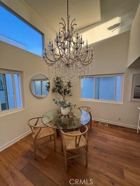 854 Cypress Ave, Hermosa Beach, CA 90254 - dining space featuring a chandelier, wood finished floors, baseboards, and a towering ceiling