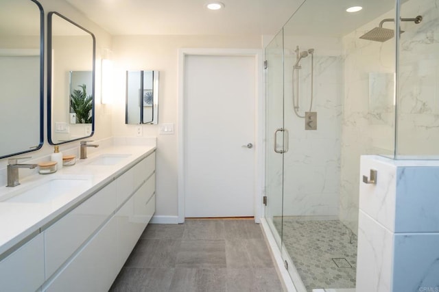 full bathroom with a marble finish shower, recessed lighting, baseboards, and double vanity
