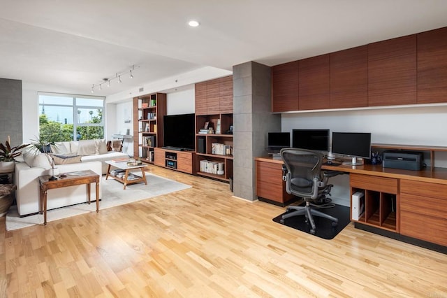 office area with light wood-type flooring, recessed lighting, track lighting, and built in desk