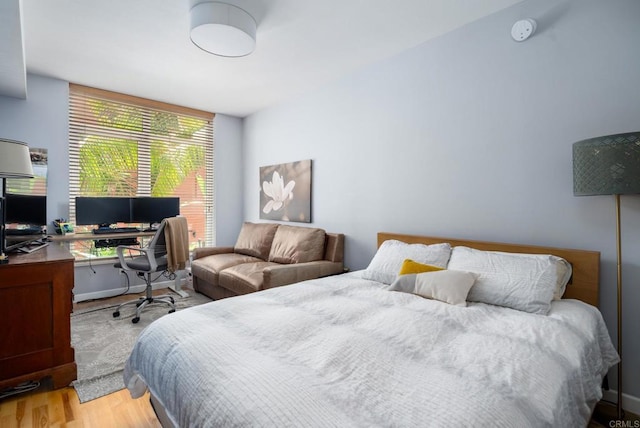 bedroom featuring light wood-style floors and an office area