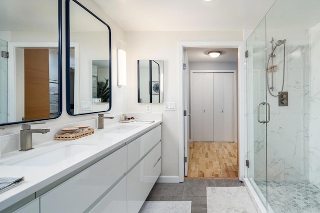 bathroom featuring a marble finish shower, double vanity, and baseboards