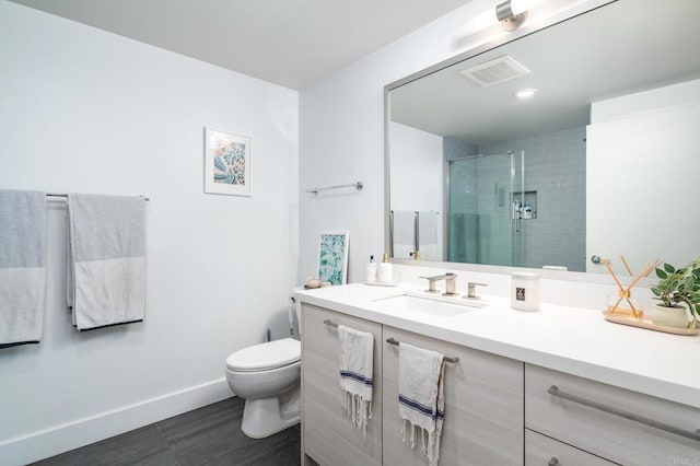 bathroom featuring a stall shower, toilet, baseboards, vanity, and recessed lighting